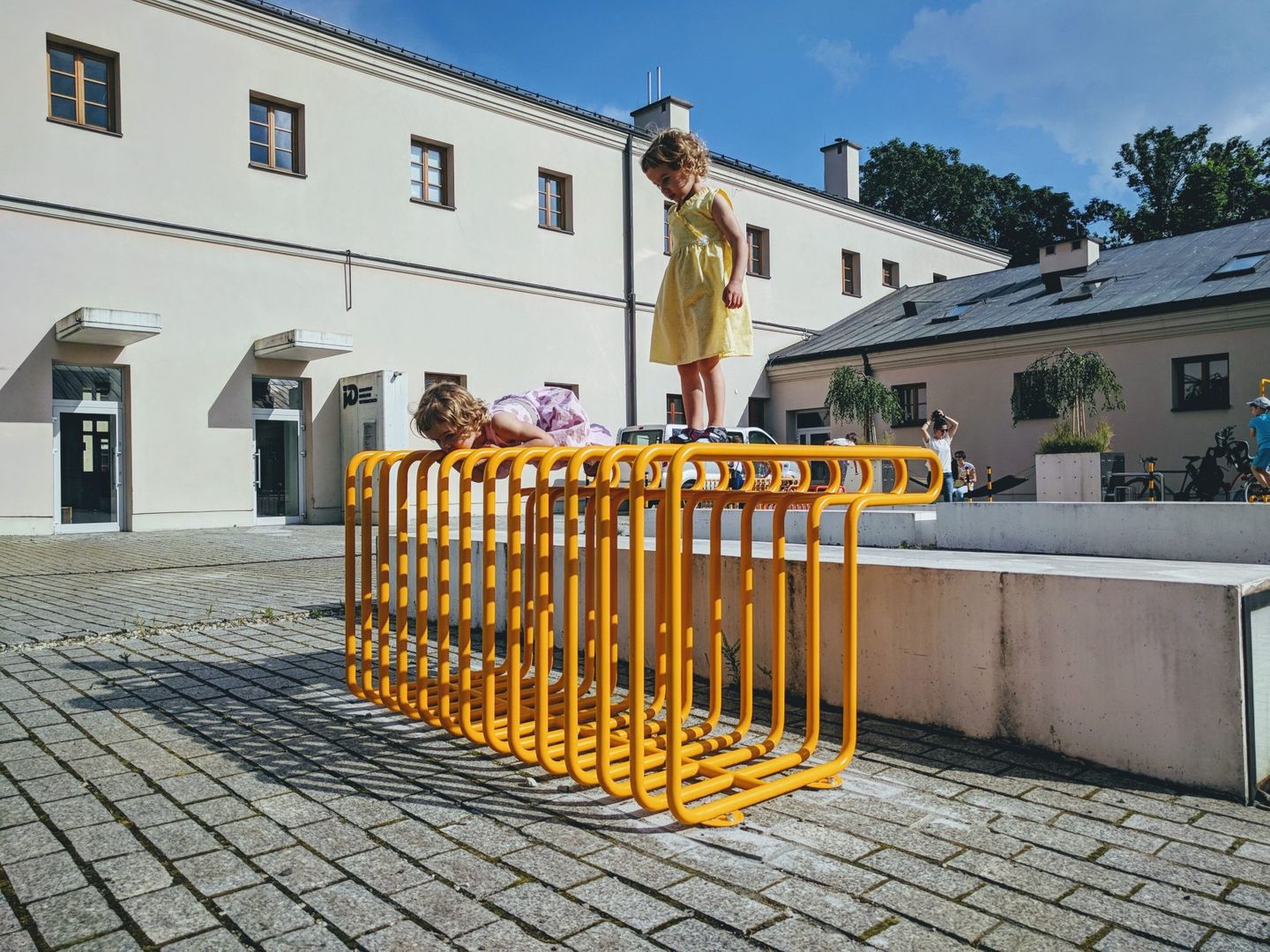 konstrukcja z żółtych, metalowych rur w przestrzeni publicznej, na niej dziecko