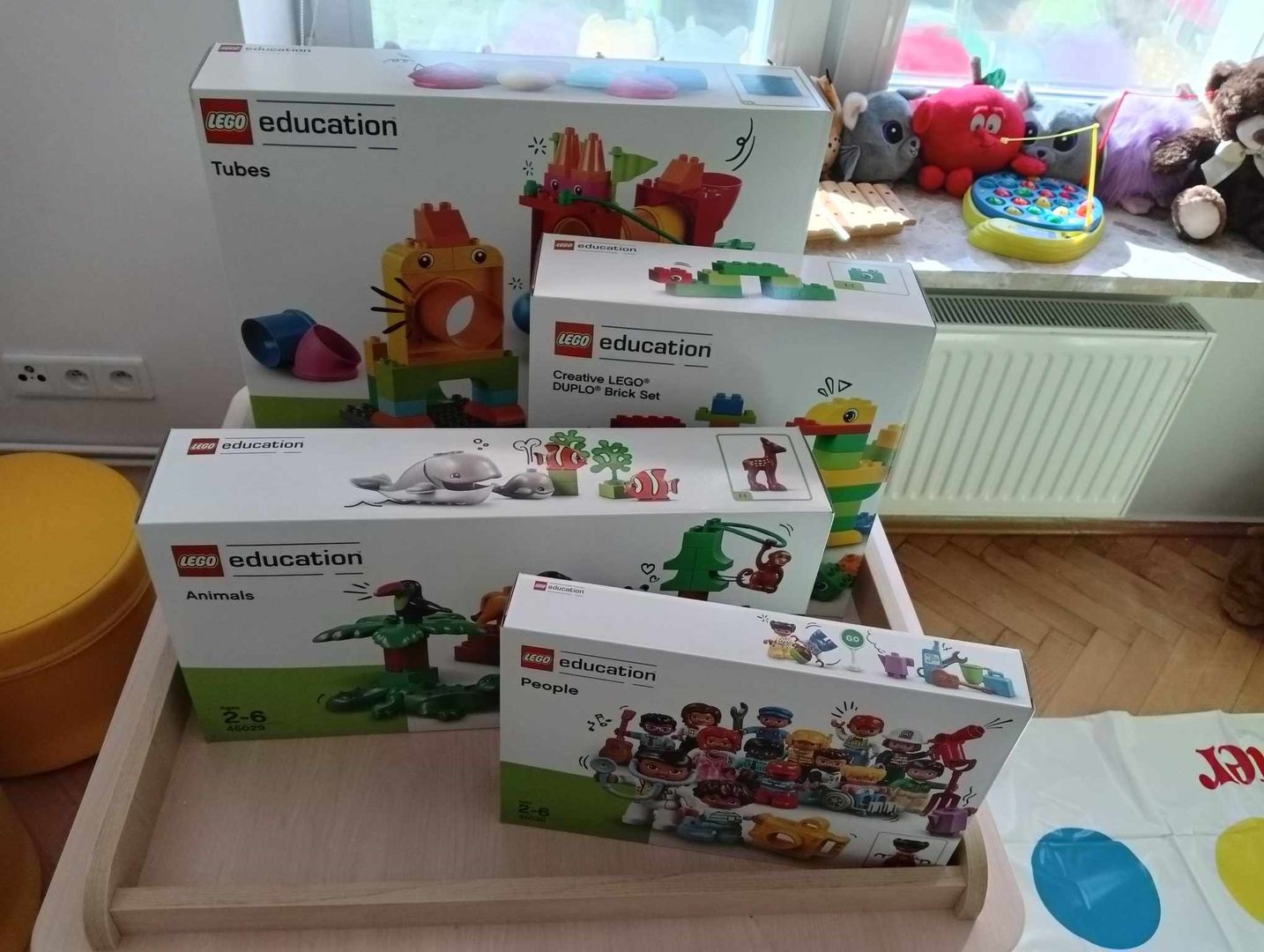 Na stoliku aktywności LEGO stoją ustawione są kompletne pudełka klocków LEGO dla dzieci.