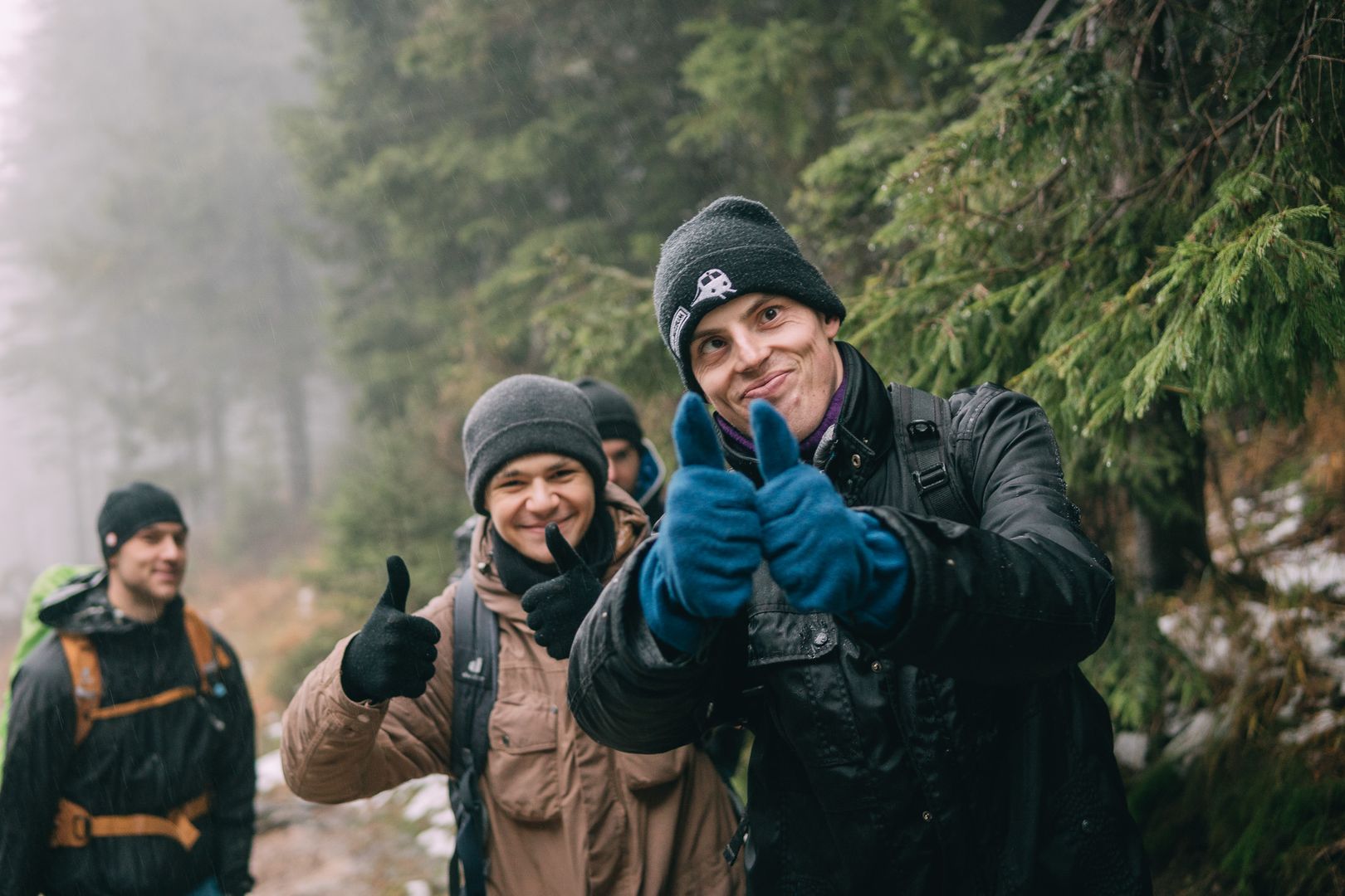 Kilku uczestników wycieczki outdoorowej unosi kciuki w górę na znak aprobaty, uśmiechają się.