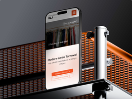 Miniatura Telefon postawiony na krawędzi srebrno pomarańczowego stołu z wizualizacją strony