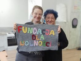 Miniatura Klub Kobiet. Dwie liderki trzymają wyszywankę z filcu z napisem "Fundacja dla Wolności"