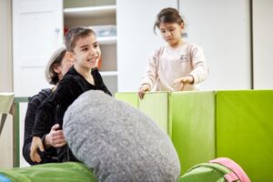 Miniatura Przystanek Świetlica. Chłopiec i dziewczynka bawią się poduszkami pod okiem wychowawczyni