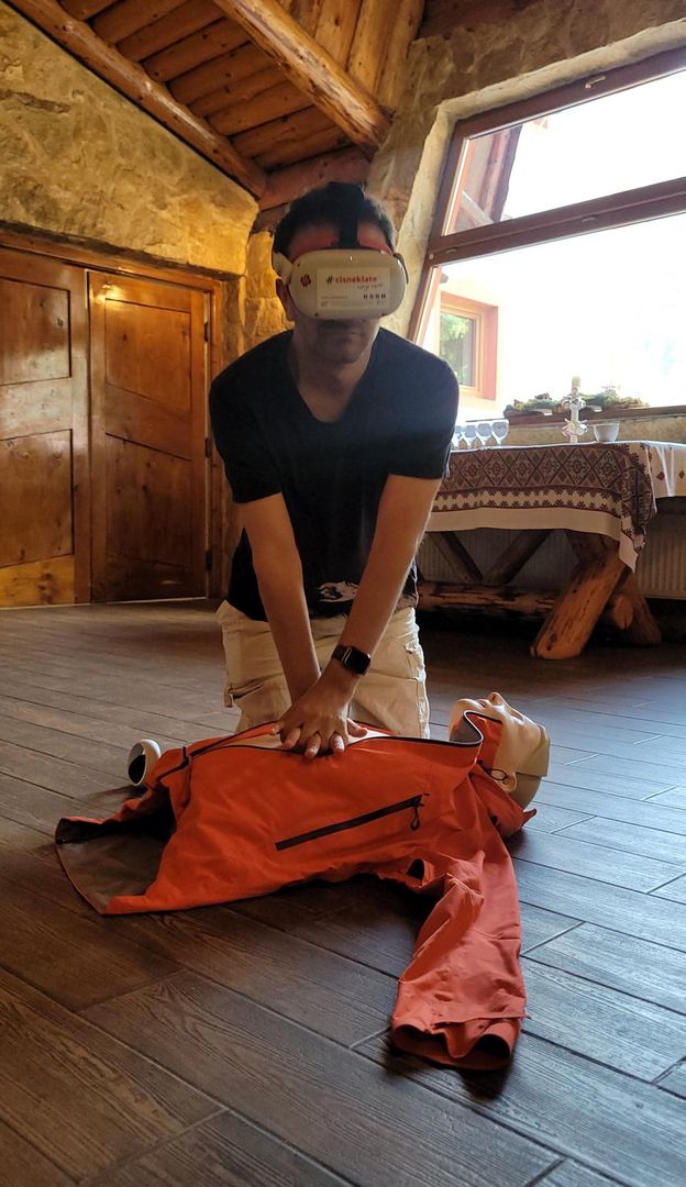 mężczyzna w goglach VR uciskający fantoma do pierwszej pomocy