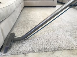 Miniatura Proces prania jasnego dywanu typu shaggy przy użyciu profesjonalnej lancy ekstrakcyjnej. Widoczne dokładne wypłukiwanie brudu z długiego włosia wykładziny. Skuteczne czyszczenie dywanów w placówkach NGO.