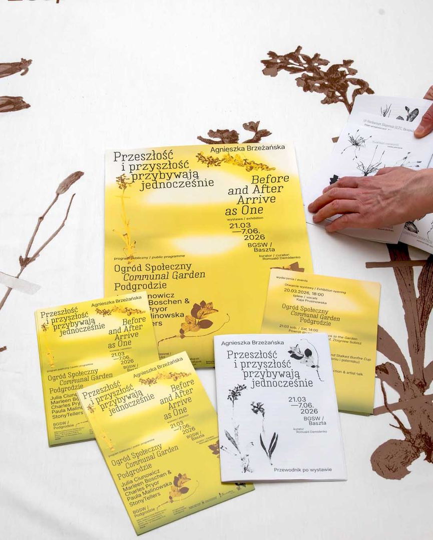 Zdjęcie przedstawia widok wydruków promocyjnych - plakatu w formacie A3 oraz ulotek i folderów A5. Są to materiały promocyjne wystawy Agnieszki Brzeżańskiej pt "Przeszłość i przyszłość przychodzą jednocześnie", wystawa odbywała się w Bałtyckiej Galerii Sztuki Współczesnej w Słupsku. 