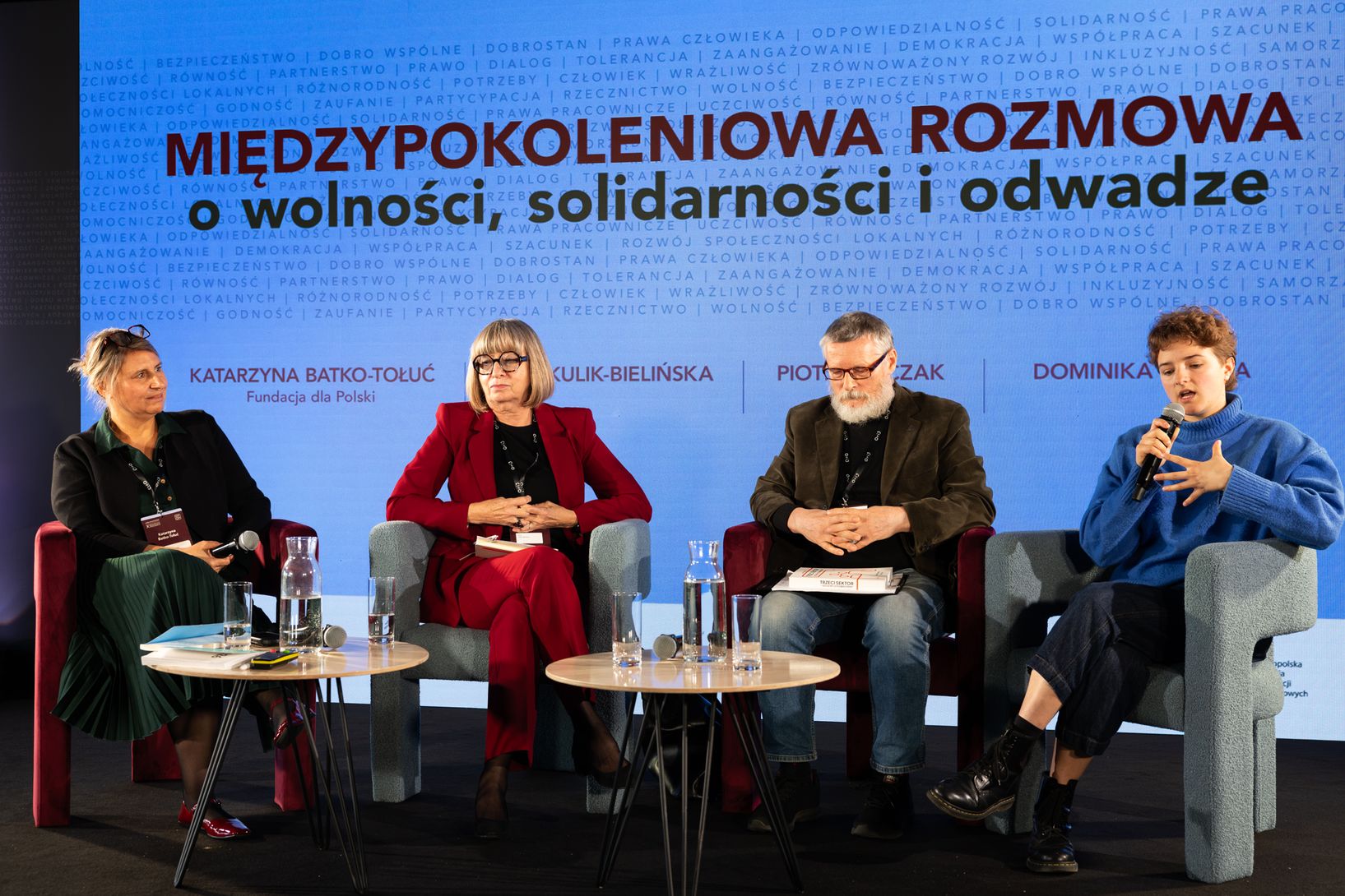 czterech prelegentów uczestniczących w panelu dyskusyjnym na scenie podczas konferencji.