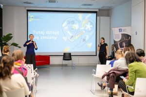 Miniatura Malwina Faza, ekspertka do spraw akceleracji, prowadzi spotkanie dotyczące tworzenia innowacji podczas konferencji Dostępna Ginekologia. Na publice są osoby o różnej sprawności. Tłumaczka PJM miga dla zgromadzonych. 
