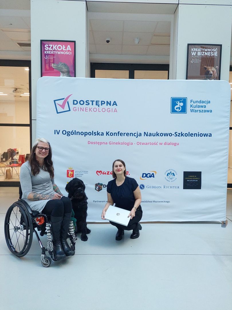 Malwina Faza, ekspertka do spraw akceleracji, pozuje z prezeską Fundacji Kulawa Warszawa. Za nimi znajduje się ścianka konferencji Dostępna Ginekologia. Pod tą samą nazwą funkcjonuje portal realizowany przez Fundację w ramach akceleracji. 